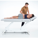 Terapeuta wykonujący mobilizację kręgosłupa w pozycji bocznej na stole Gymna.PRO.