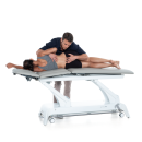 Terapeuta wykonujący technikę mobilizacji odcinka lędźwiowego na stole Gymna.PRO.