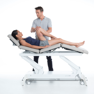 Terapeuta wykonujący mobilizację nogi pacjentki na stole Gymna.PRO Q z regulowanym oparciem.