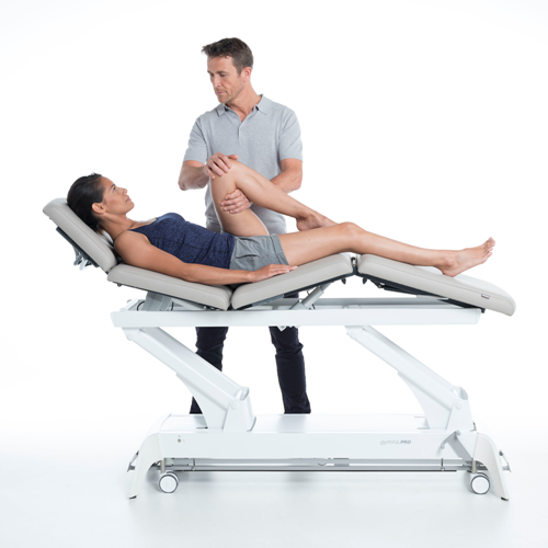 Terapeuta wykonujący mobilizację nogi pacjentki na stole Gymna.PRO Q z regulowanym oparciem.