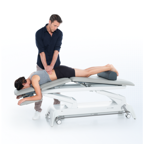 Terapeuta wykonujący ucisk na dolny odcinek kręgosłupa pacjentki na stole Gymna.PRO.