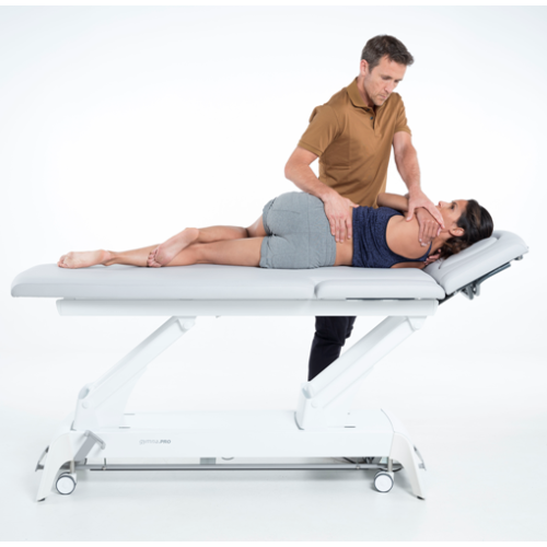 Terapeuta wykonujący mobilizację kręgosłupa w pozycji bocznej na stole Gymna.PRO.